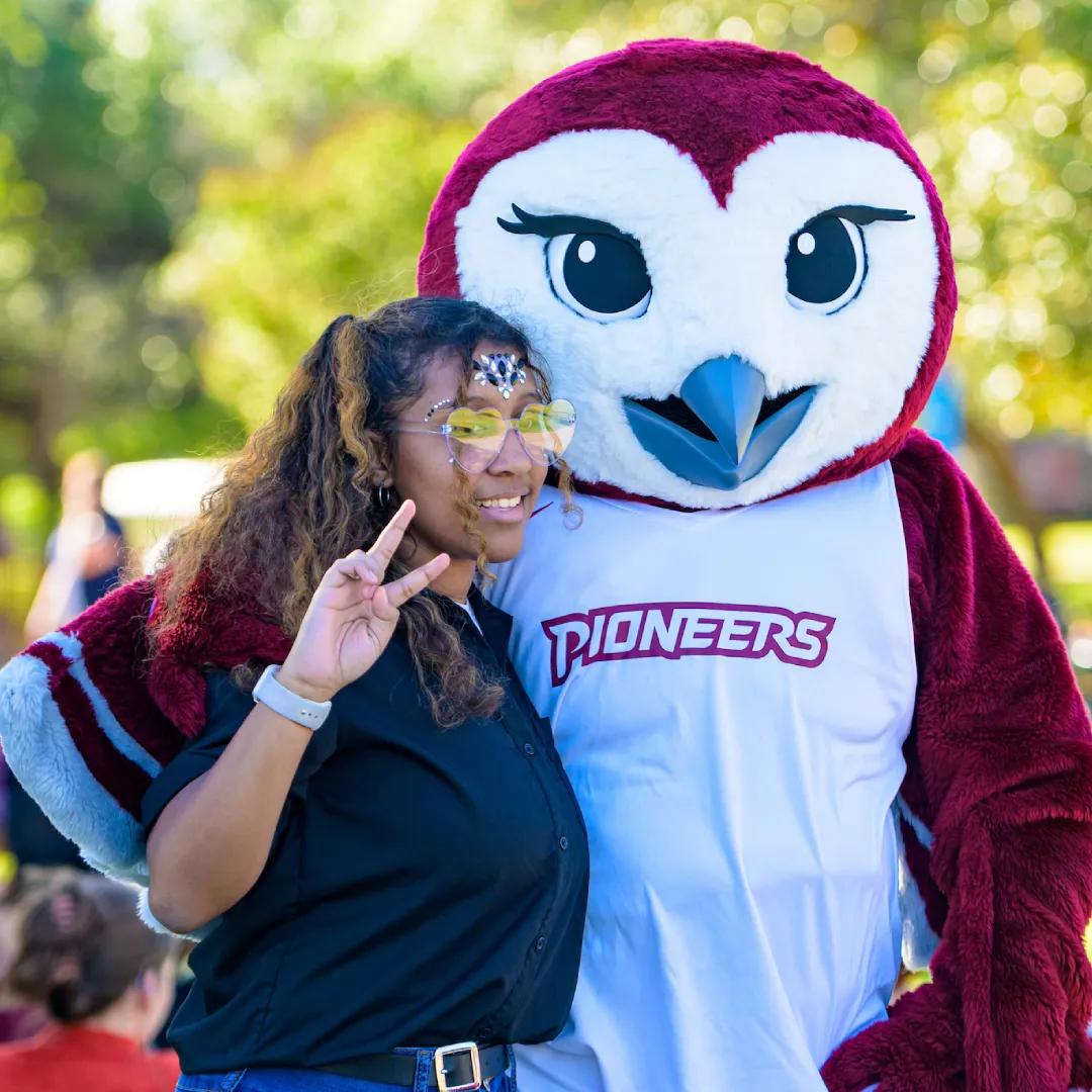 A young woman gives a peace sign while posing with Oakley at a TWU event.