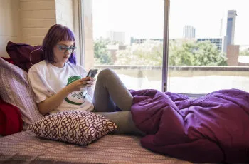 Student reading in her bed by the window.